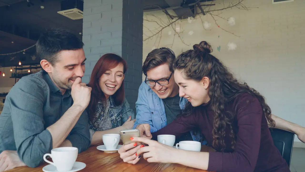Amigos mirando un teléfono en un café